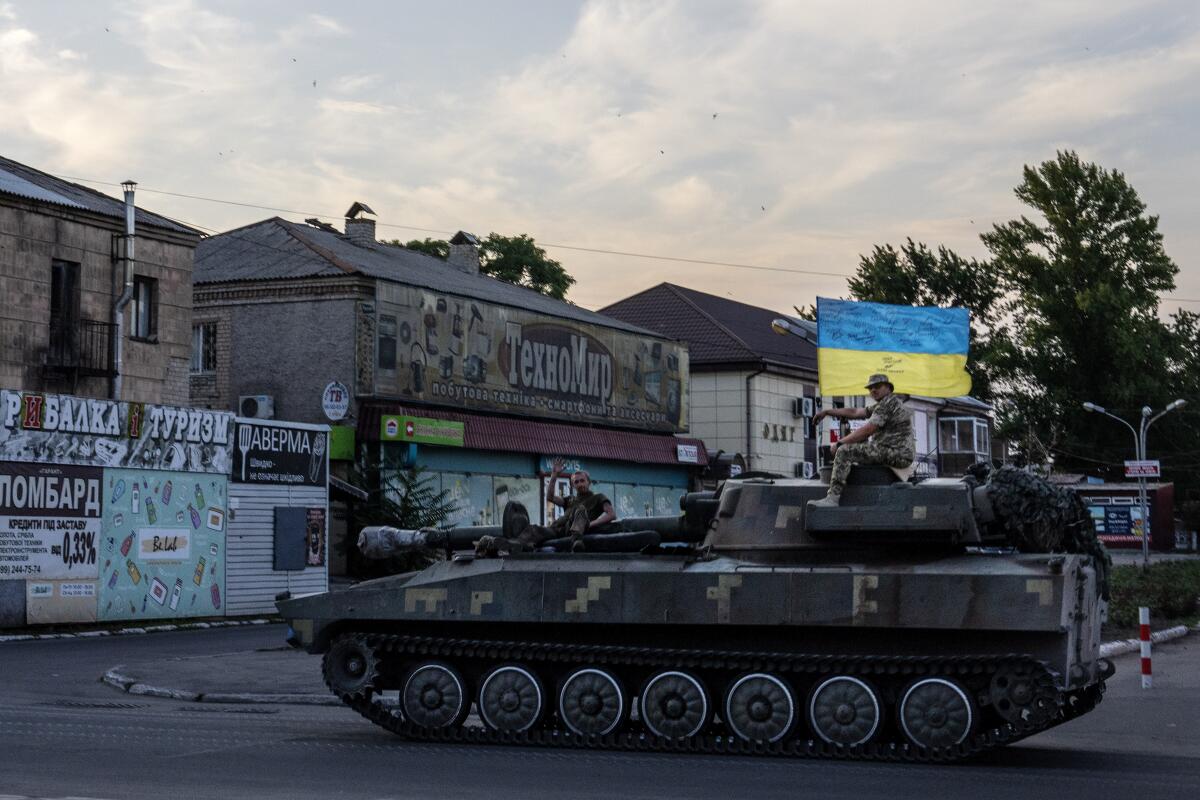 Ukrainian soldiers ride atop a tank through a street in Pokrovsk, Donetsk region, eastern Ukraine.