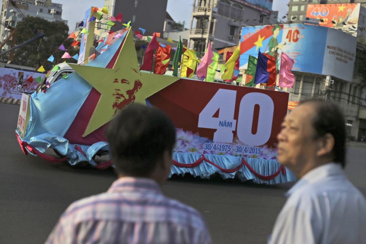 Vietnamese men watch as a float drives past by during a parade ahead of the celebration of the 40th anniversary of the end of the Vietnam War in Ho Chi Minh City, formerly known as Saigon, on April 29.