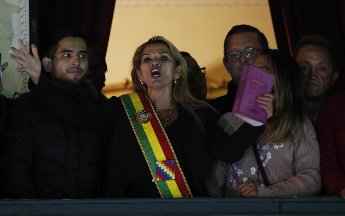 Jeanine Añez, wearing the Bolivian presidential sash and holding a Bible, addresses the crowd from the balcony of the presidential palace in La Paz after promoting herself to the head of the Senate on Tuesday.