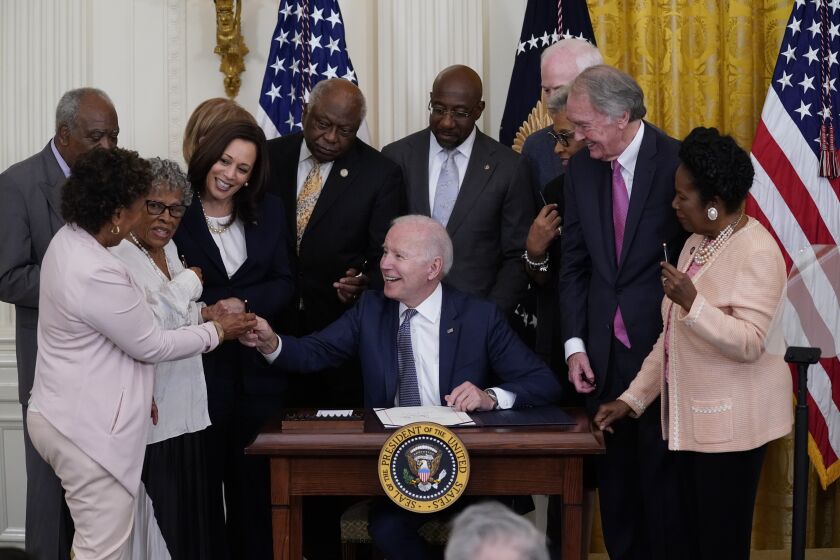 President Joe Biden hands a pen to Rep. Barbara Lee, D-Calif, after signing the Juneteenth National Independence Day Act, in the East Room of the White House, Thursday, June 17, 2021, in Washington. From left, Lee, Rep. Danny Davis, D-Ill., Opal Lee, Sen. Tina Smith, D-Minn., obscured, Vice President Kamala Harris, Clyburn, Sen. Raphael Warnock, D-Ga., Sen. John Cornyn, R-Texas, Rep. Joyce Beatty, D-Ohio, obscured, Sen. Ed Markey, D-Mass., and Rep. Sheila Jackson Lee, D-Texas. (AP Photo/Evan Vucci)