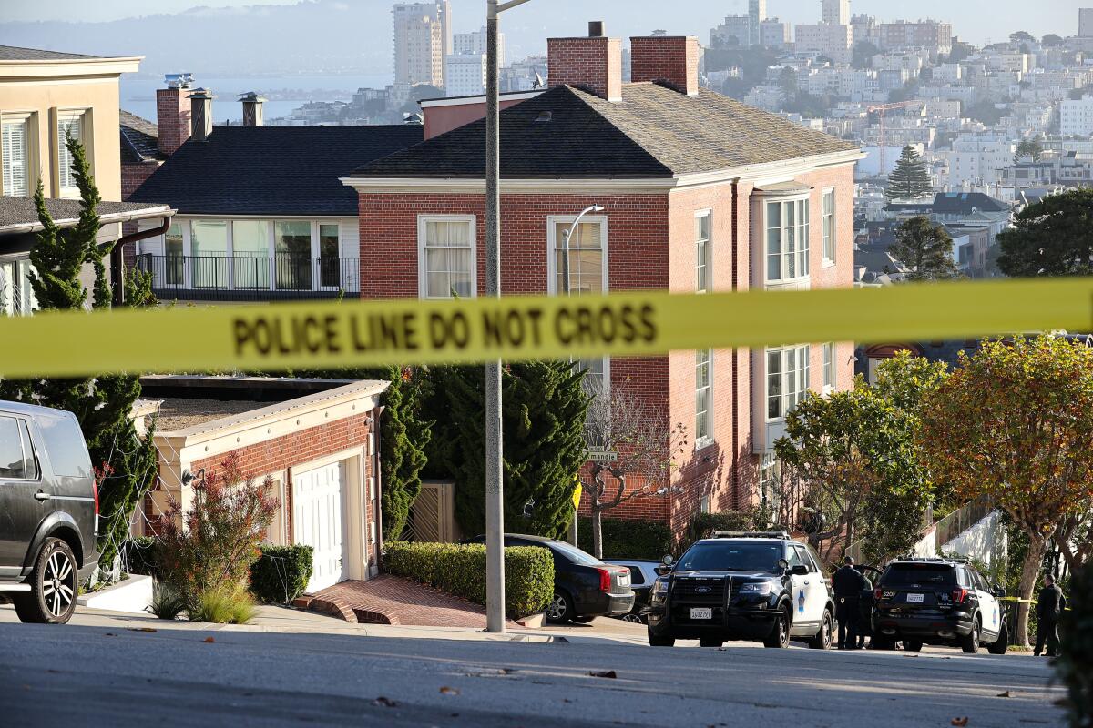 Police and police cars outsidee houses on a hillside 