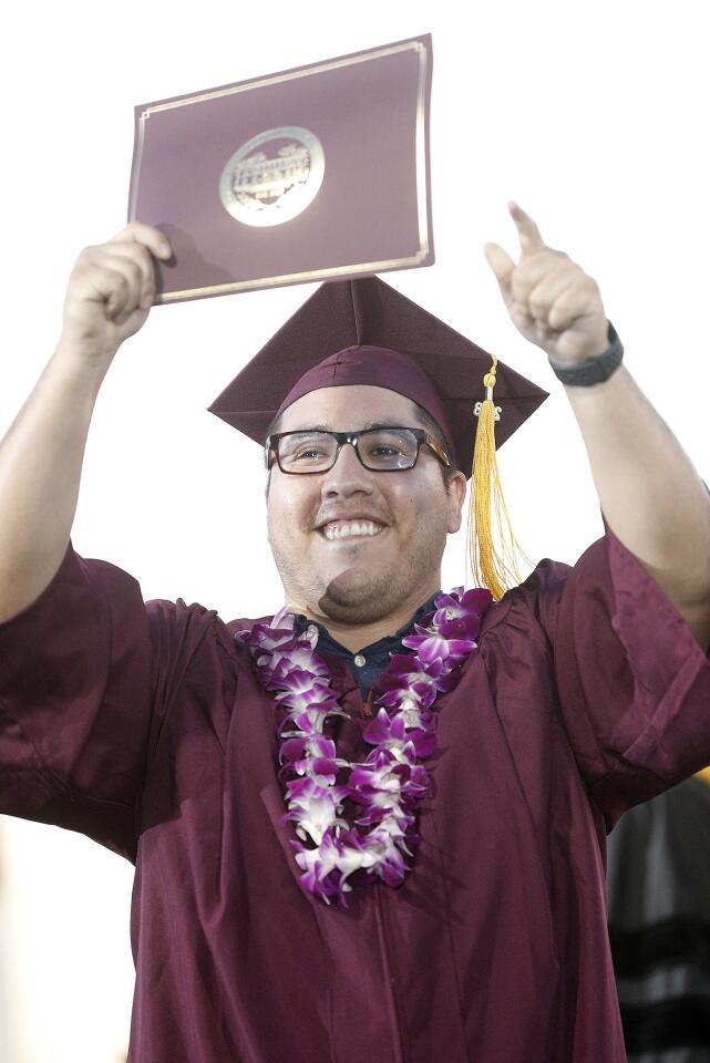 The last graduate in the ceremony to walk the stage Hulberth Marrouquin holds up his diploma at the graduation ceremony for the Glendale Community College class of 2018 on Wednesday, June 13, 2018.