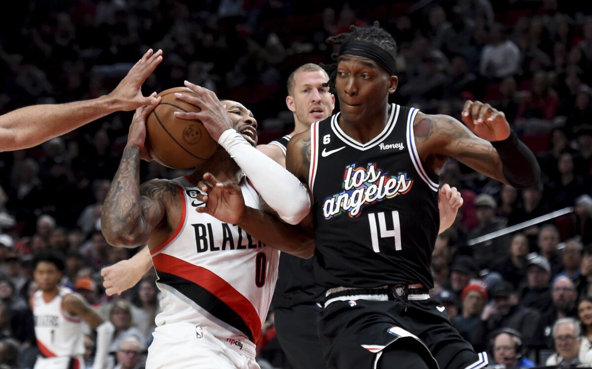 Portland Trail Blazers guard Damian Lillard, left, drives against Los Angeles Clippers guard Terance Mann, right, during the first half of an NBA basketball game in Portland, Ore., Sunday, March 19, 2023. (AP Photo/Steve Dykes)
