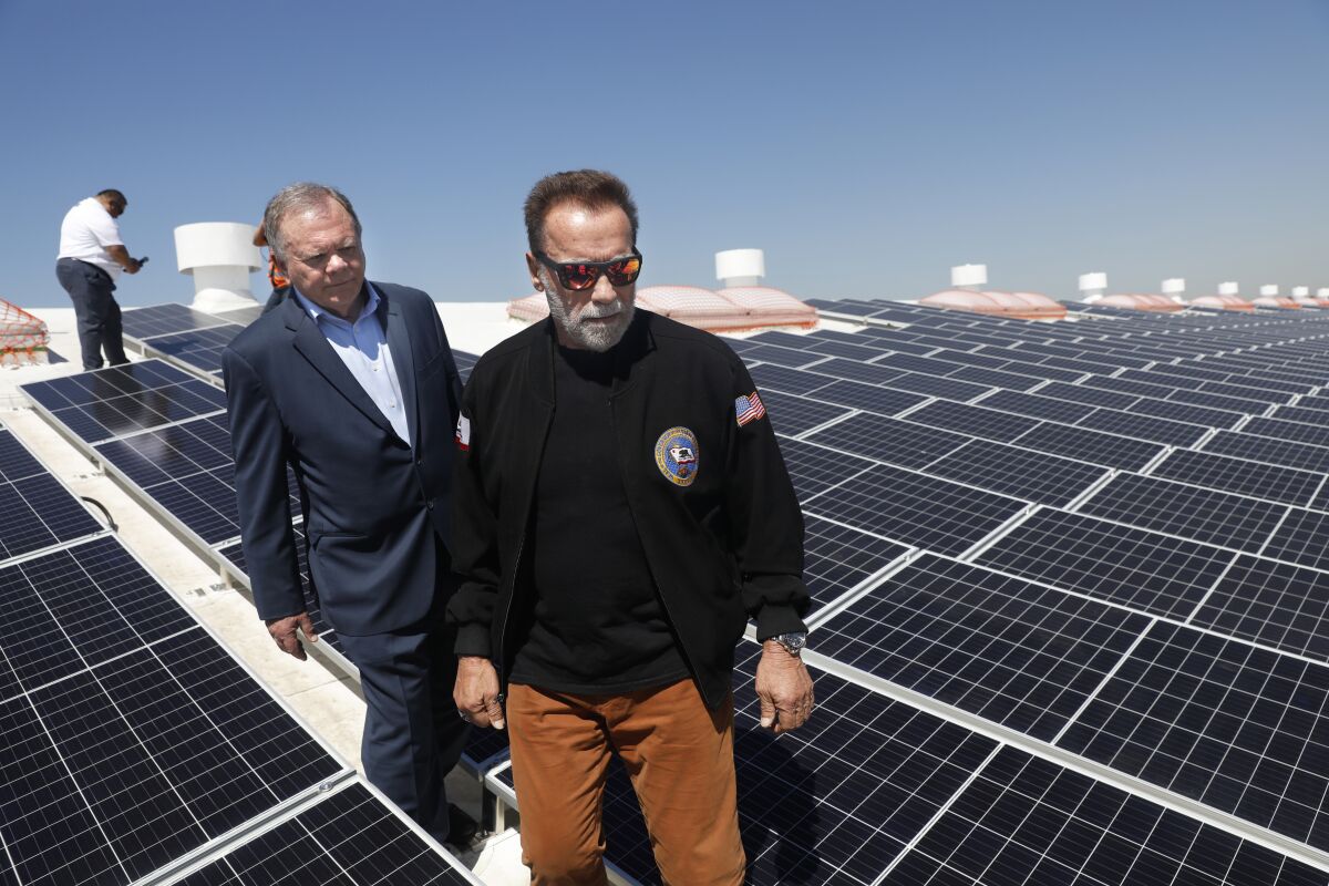 Arnold Schwarzenegger, center, tours a rooftop solar installation at the Port of Los Angeles in April.