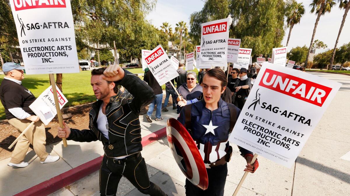 Dressed as comic book characters, Ross Michael Johnson and Henry Hodge, right, joined SAG-AFTRA picketers on strike outside the Electronic Arts campus in Playa Vista on Oct. 24.