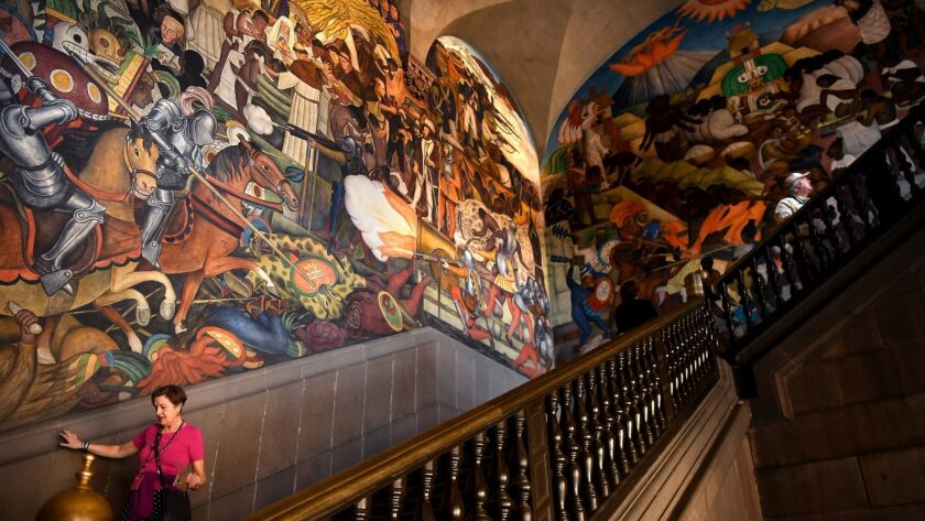 A woman walks by a huge mural painted by famous Mexican artist Diego Rivera inside the Palacio Nacional in Mexcio City.
