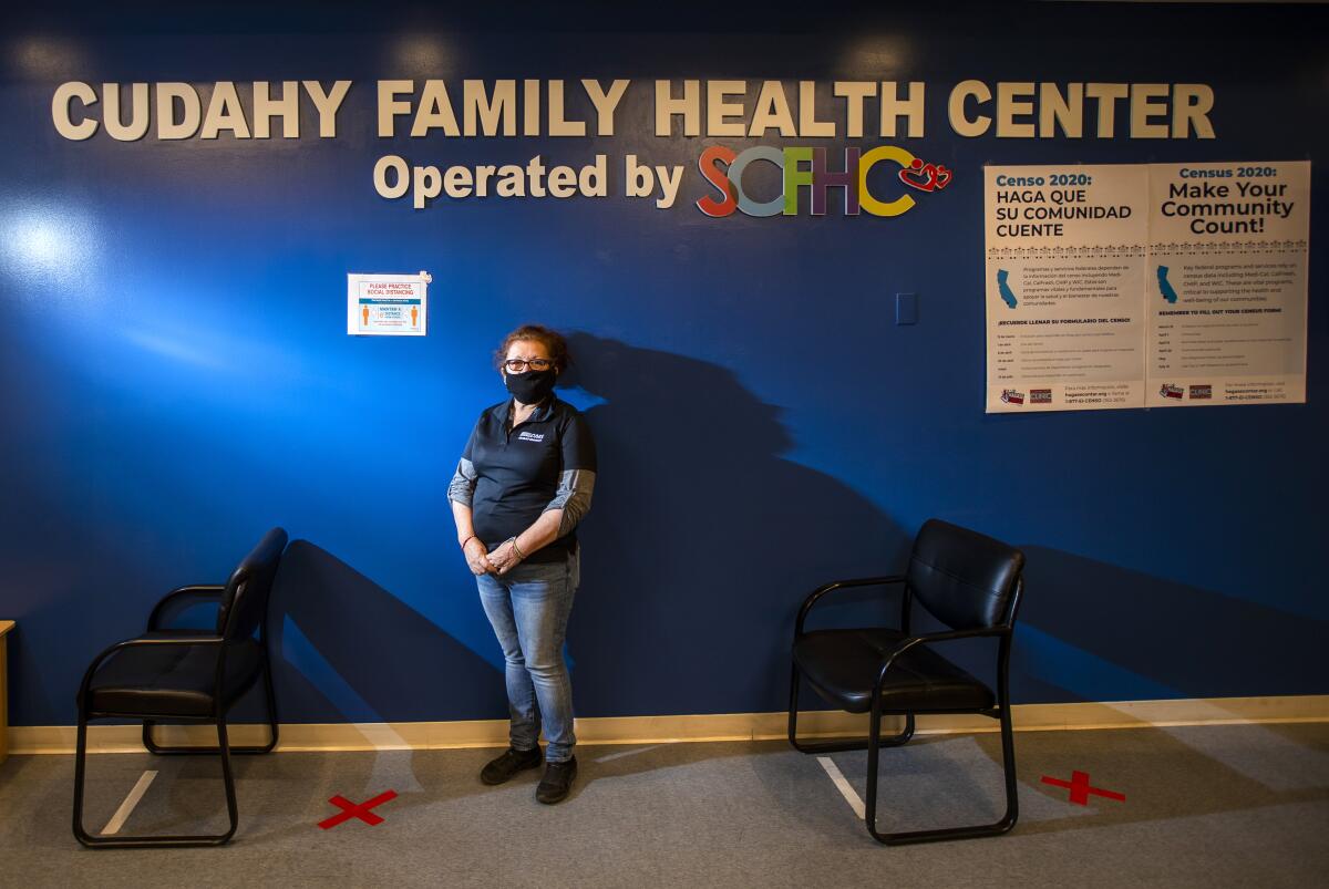 Alma Rosa Calvillo stands by a wall with lettering: "Cudahy Family Health Center."