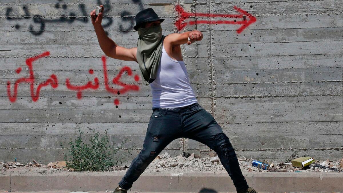 A Palestinian lobs a stone at Israeli security forces in the West Bank city of Hebron on July 21, 2017.