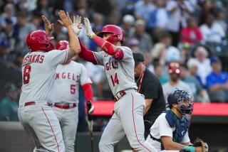 Los Angeles Angels' Logan O'Hoppe (14) is greeted by teammate Mike Moustakas (8) after scoring.