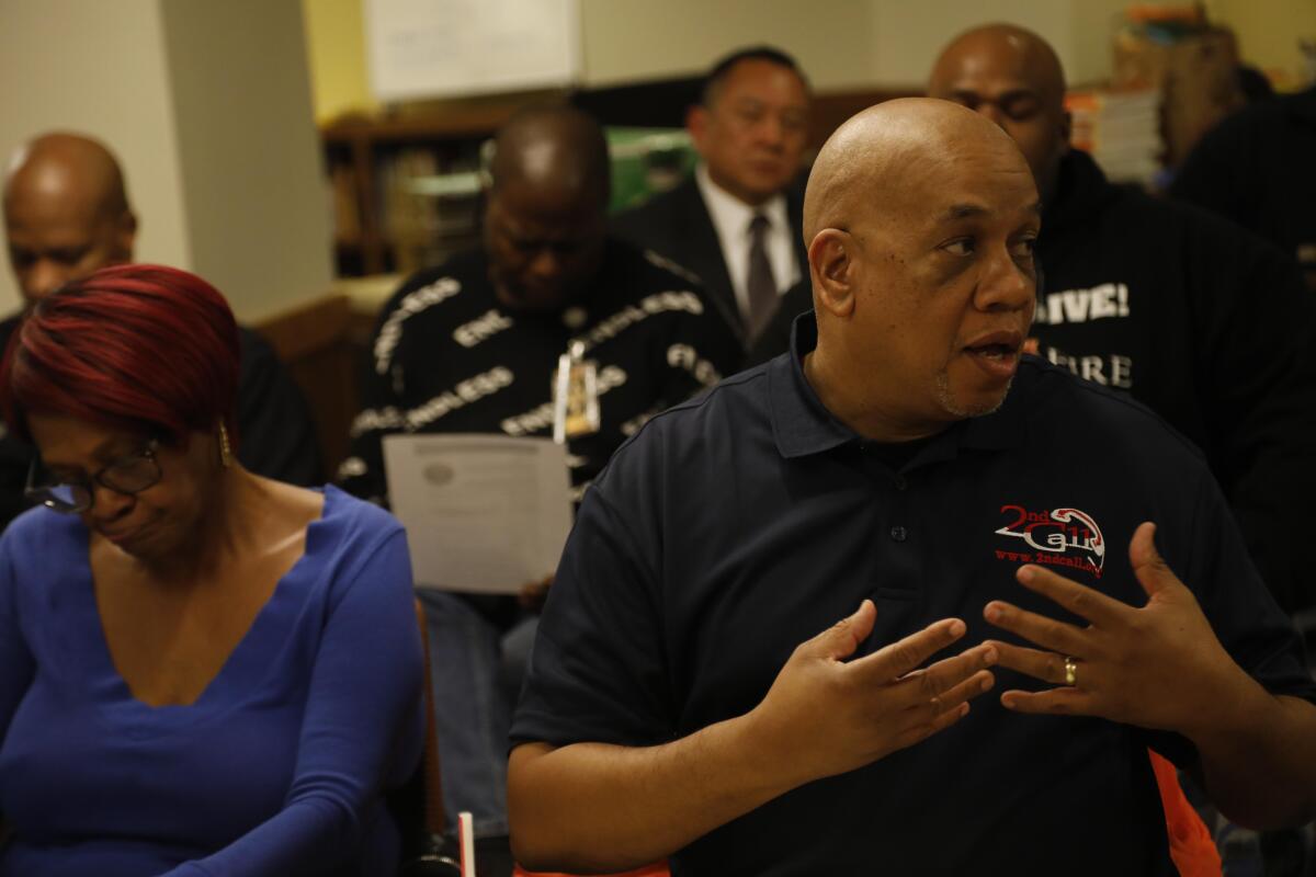 A man gestures with both hands raised to his chest.