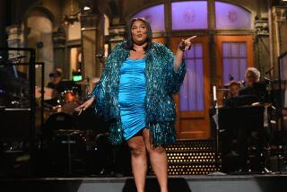 A woman wearing a turquoise dress and sparkly fringe jacket on a stage