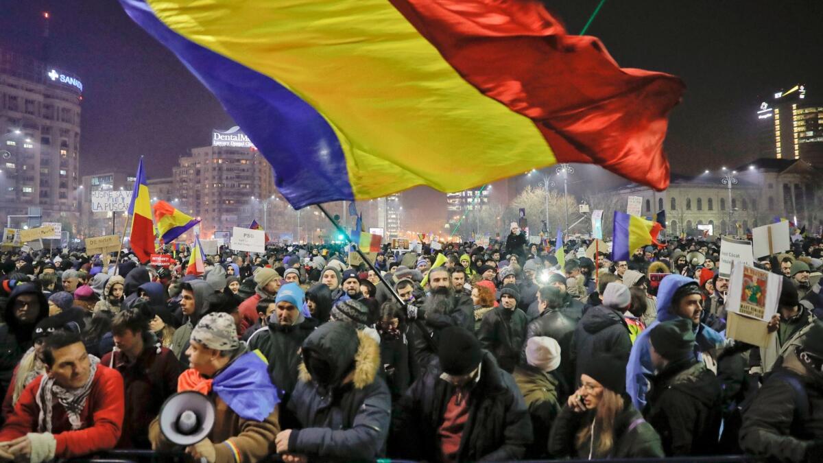 A man waves a large Romanian flag in Bucharest, Romania, on Thursday during a protest by tens of thousands against a government decree that dilutes what qualifies as corruption.