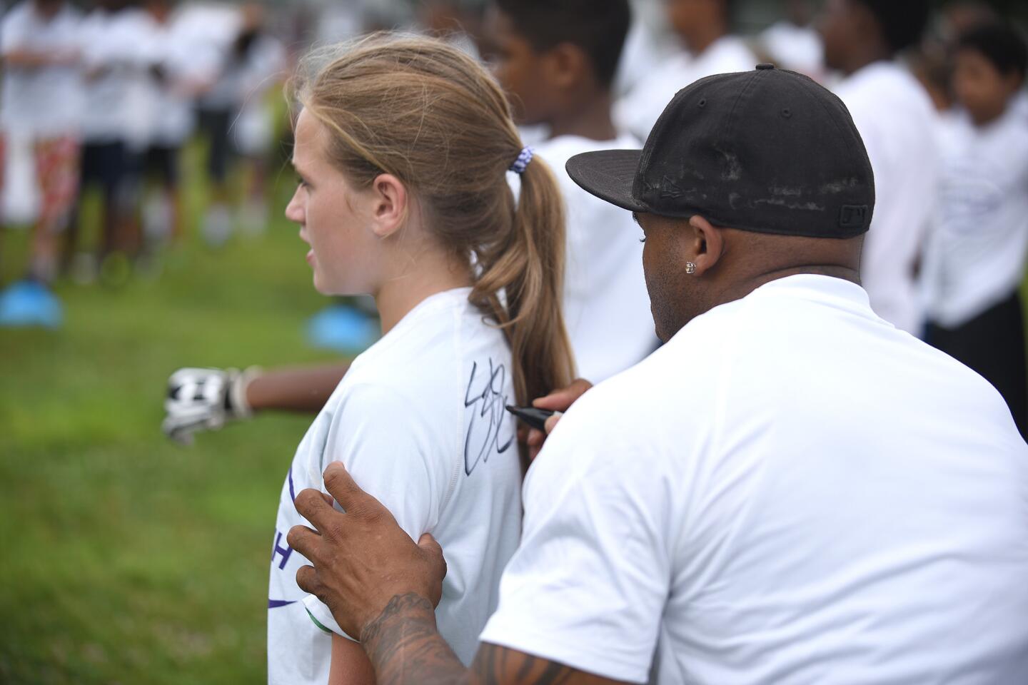 Ravens wide receiver Steve Smith autograph the T-shirt of football player Carlee Maltba during his football clinic at Owings Mills High School.