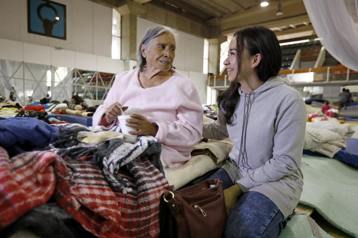 Refugio Gonzalez, 85, left, is comforted by volunteer Lety Rebollar, 19, of Mexico State, in a shelter holding 460 people displaced by the earthquake at Centro Deportivo Benito Juarez sports complex in Mexico City.