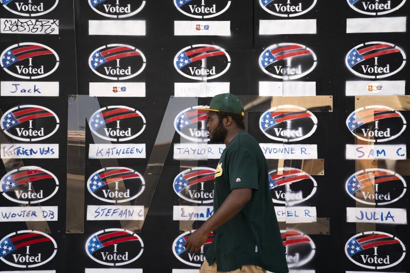 A man walks past a boarded-up store painted with "I Voted" signs ahead of Election Day Monday