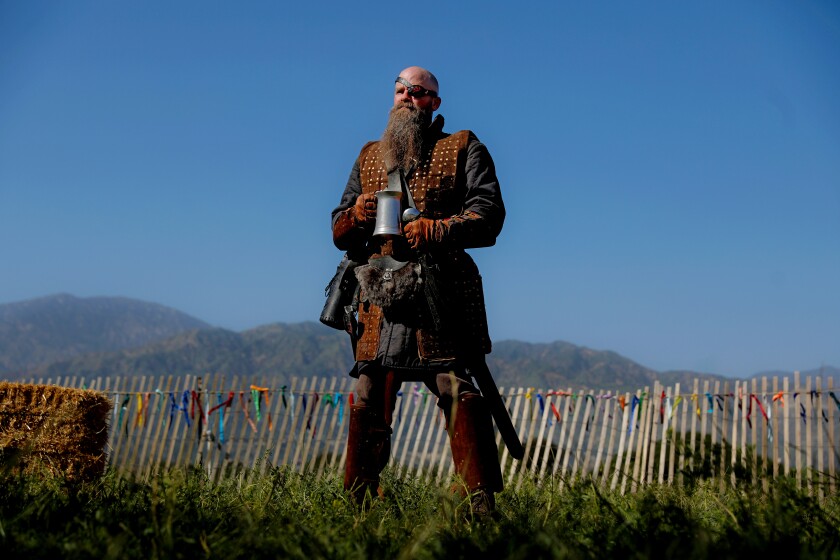 A man wearing armor holds a drinking flagon.