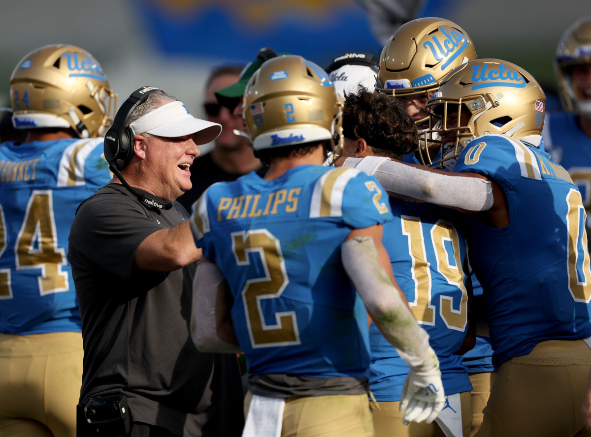 UCLA coach Chip Kelly gathers with players on the sideline to celebrate a touchdown against rival USC