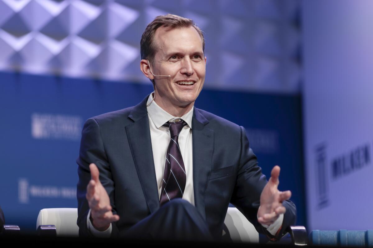 George Whitesides gestures while wearing a suit and headset microphone at a 2019 conference