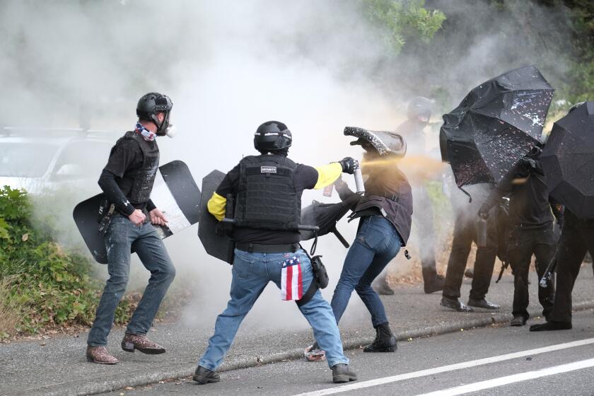 FILE - Members of the far-right group Proud Boys and anti-fascist protesters spray bear mace at each other during clashes between the politically opposed groups in Portland, Ore., Aug. 22, 2021. Over the past decade, Oregon experienced the sixth-highest number of extremist incidents in the nation, despite being 27th in population, according to an Oregon Secretary of State report. Now, the state Legislature is considering a bill that, experts say, would create the nation's most comprehensive law against paramilitary activity. (AP Photo/Alex Milan Tracy, File)