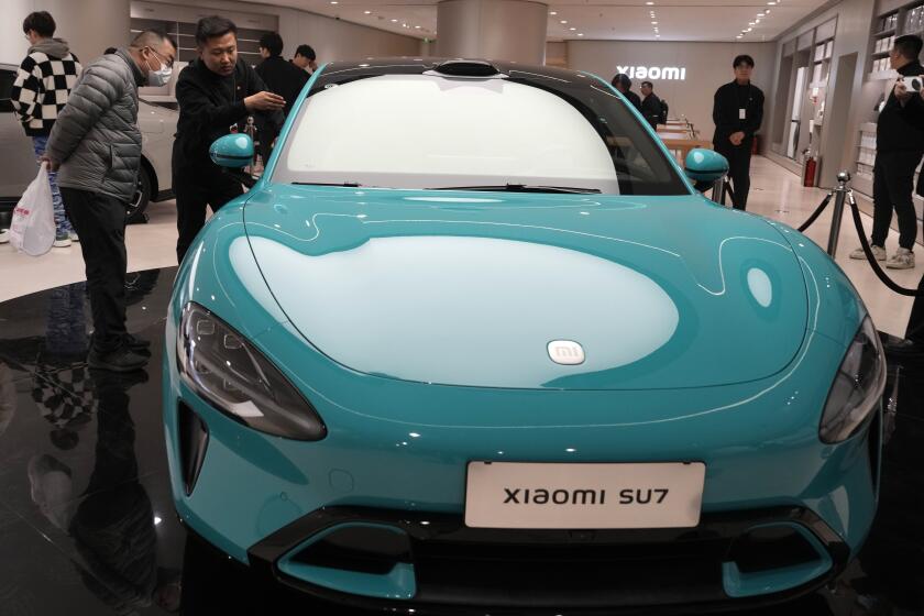 Visitantes contemplan el auto eléctrico Xiaomi SU7 en exhibición en el salón Xiaomi en Beijing, 26 de marzo de 2024. Xiaomi, un conocido fabricante de productos electrónicos de consumo en China, se suma al concurrido boom de los autos eléctricos con un sedán de aspecto deportivo y alta tecnología. (AP Foto/Ng Han Guan)