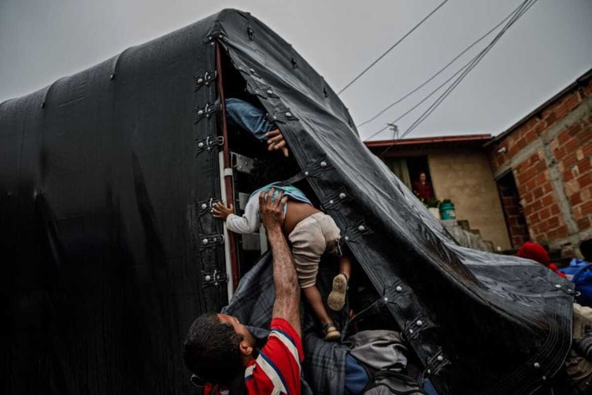 Un pequeño es subido a la parte trasera de un camión mientras los migrantes se apresuran a hacer autostop en el frígido Páramo de Berlín en su peligroso viaje para escapar de Venezuela a través de Colombia.
