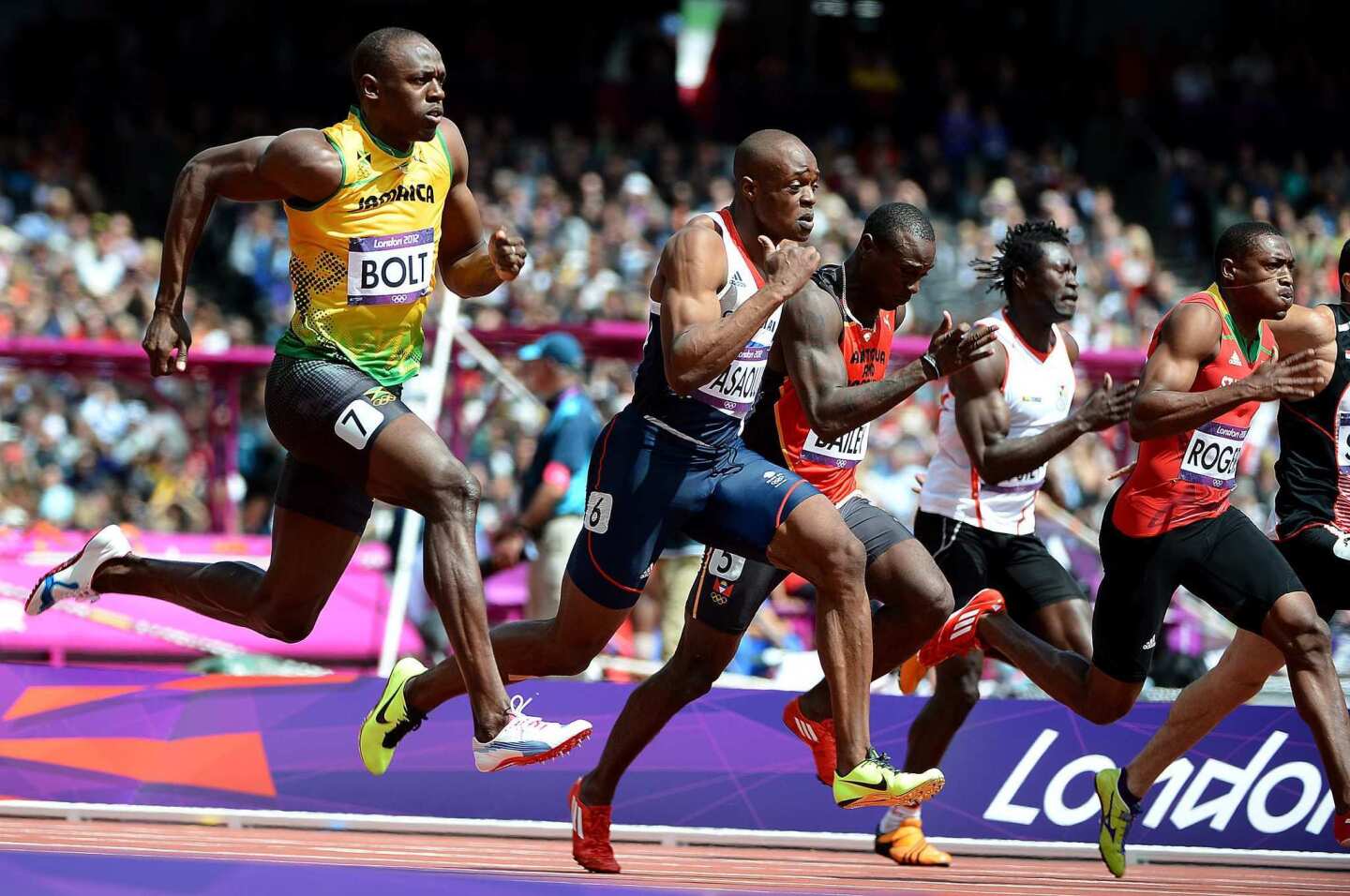 Jamaica's Usain Bolt, left, wins his qualifying heat of the 100- meter race.