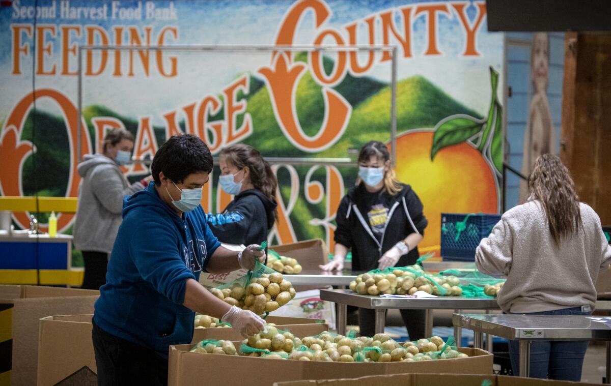 Jose Secundino, foreground, joins Second Harvest Food Bank employees as they pack boxes of food for the needy.