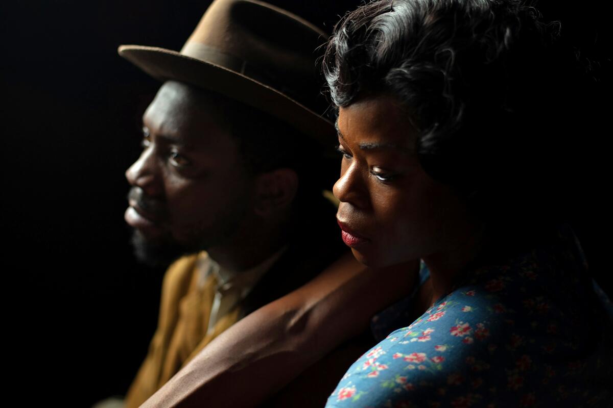 A man and a woman in 1950s era clothing, looking somber