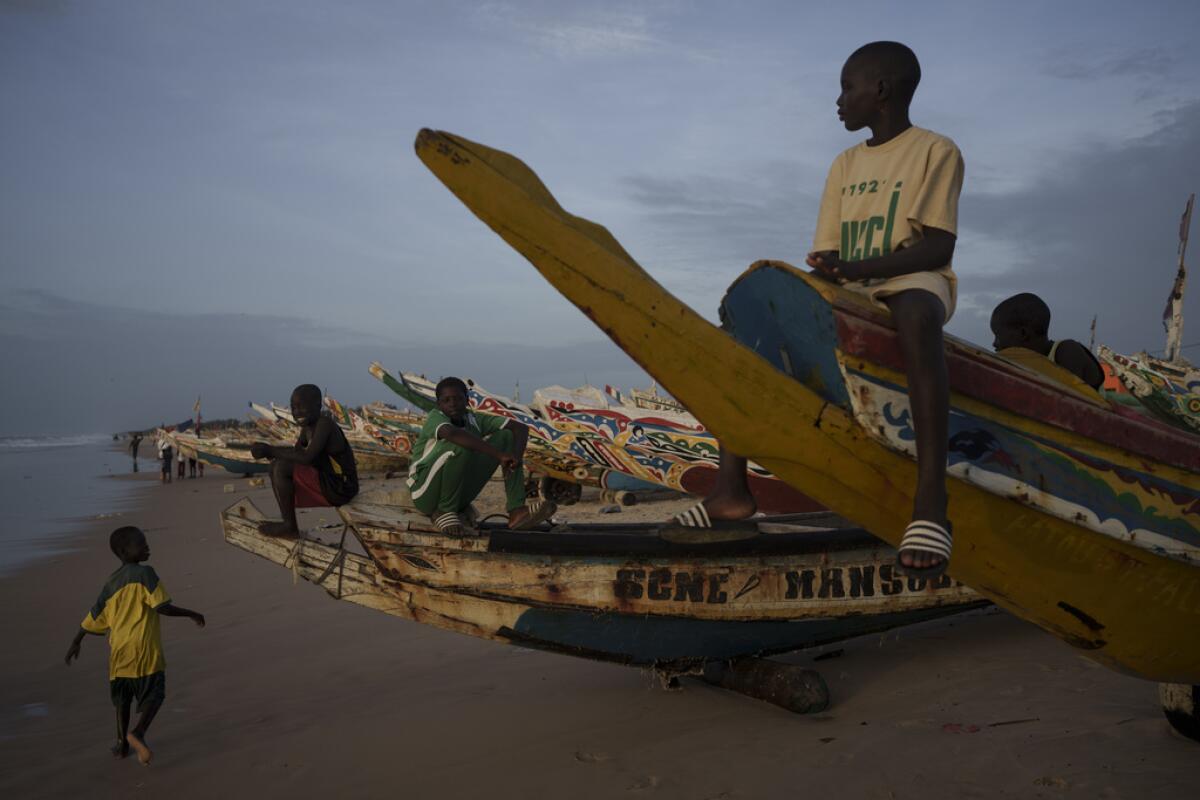 Niños sentados en piraguas, embarcaciones senegalesas