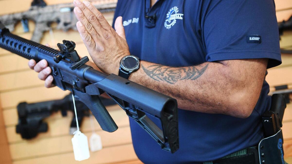 A salesman at a Virginia gun store demonstrates an AR-15 rifle fitted with a bump stock.
