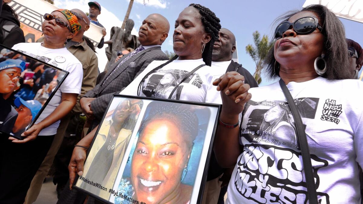 Lisa Hines holds a photo of her daughter, Wakiesha Wilson, during a rally in Watts a year after Wilson's 2016 death in an LAPD jail cell.