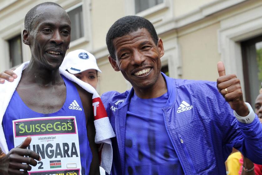 Kenneth Mungara, left, celebrates with Ethiopian long-distance running great Haile Gebrselassie after winning a marathon in Milan, Italy, on April 12, 2015.