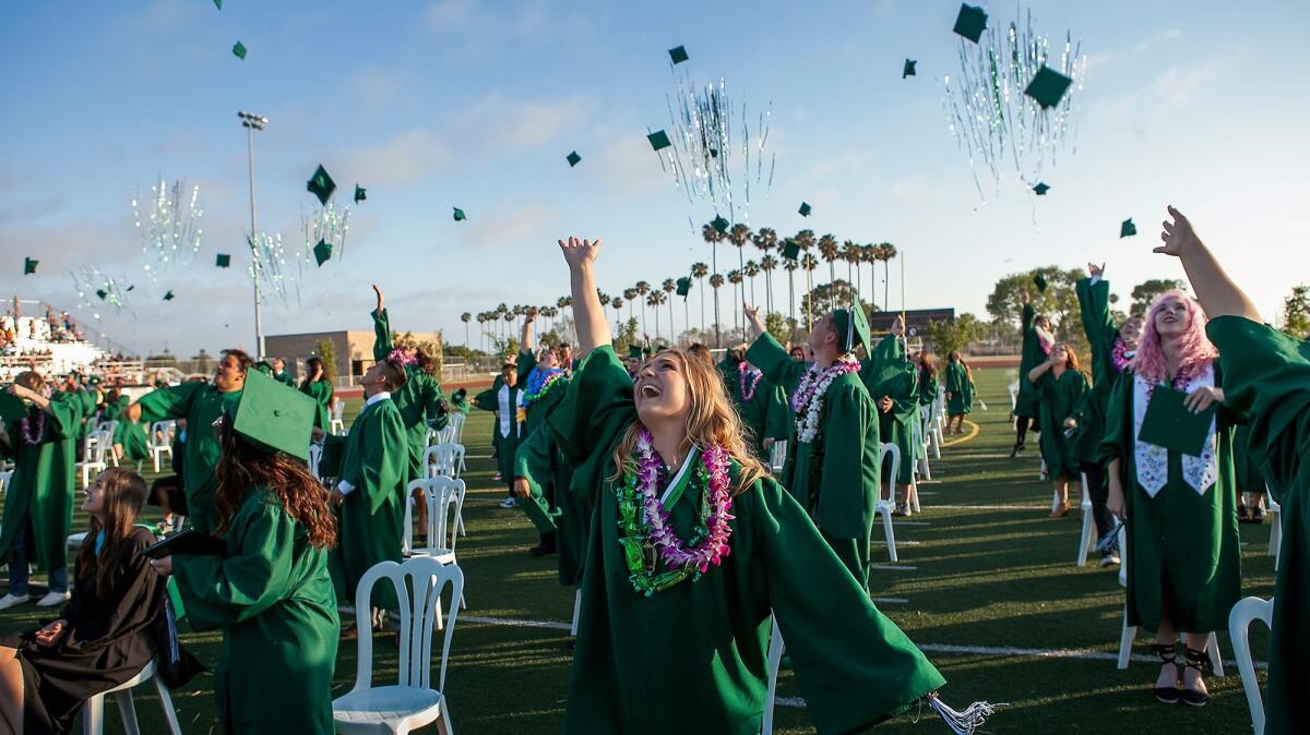 Emily Neppl, center, along with the rest of her class toss their caps in the air during the 2016 commencement ceremony for Costa Mesa High School.