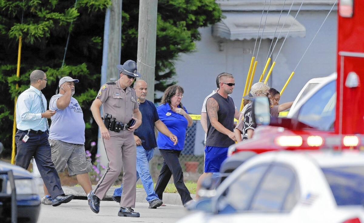 A Florida state trooper escorts a group of parents to a day-care center to pick up their children after a vehicle crashed into the building in Winter Park.