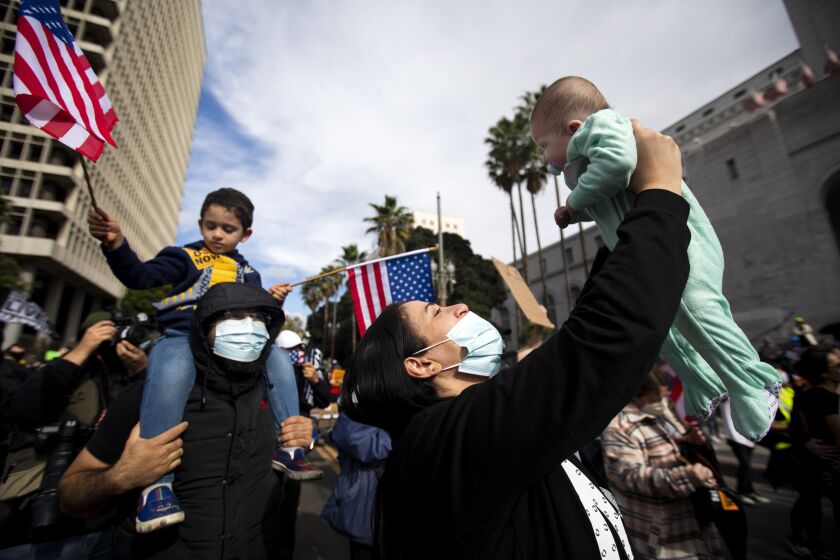 Los Angeles, CA NOVEMBER 7, 2020: Mother Abeer Mahmoud, 35, holds Asset Taha, age 3, right, months up into the air as they participate in the celebration outside Los Angeles City Hall. Joe Biden was elected the 46th president of the United States on Saturday when Pennsylvania and Nevada delivered the electoral votes he needed to claim the White House, ending a caustic campaign that sorely tested the nation amid a pandemic and deep partisan divisions. During a the global coronavirus pandemic thousands of people celebrate the election peacefully in downtown Los Angeles November 7, 2020. (Francine Orr/ Los Angeles Times)