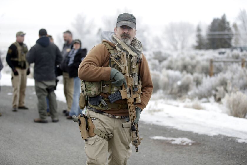 FILE--In this Jan. 9, 2016, file photo, a man stands guard after members of the "3% of Idaho" group along with several other organizations arrived at the Malheur National Wildlife Refuge near Burns, Ore., Federal wildlife employees will again be barred from testifying about any fear they felt during last winter's armed occupation of a national bird sanctuary in southeastern Oregon. (AP Photo/Rick Bowmer, file)
