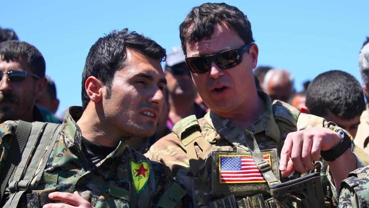 This file photo taken on April 25, 2017, shows a U.S. officer, right, speaking with a fighter from the Kurdish People's Protection Units at the site of Turkish airstrikes near the northeastern Syrian Kurdish town of Derik.