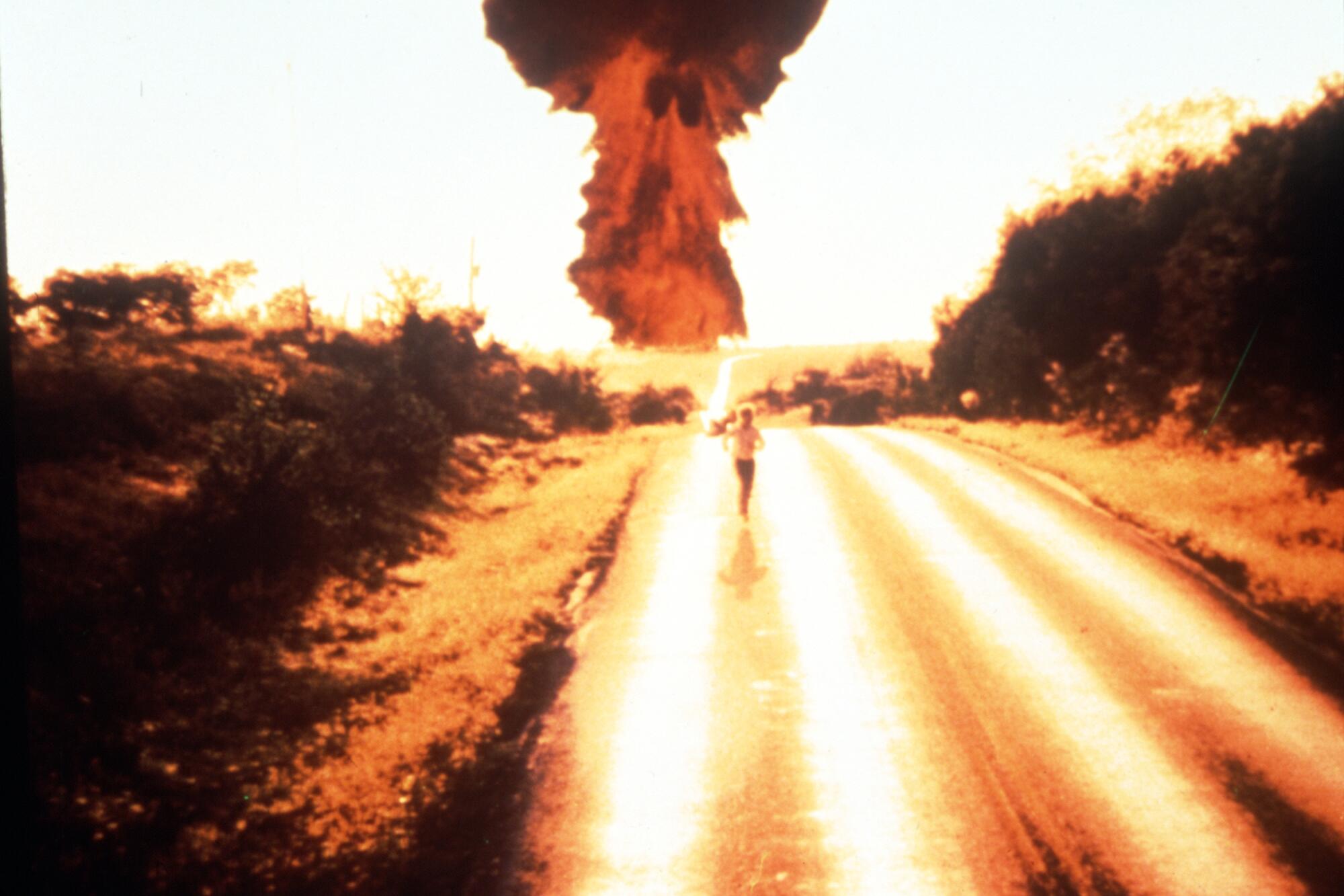 A person runs down the road away from a mushroom cloud in the movie "The Day After."
