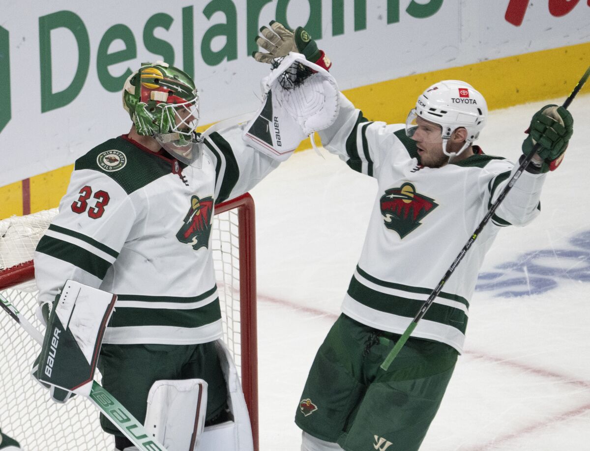 Minnesota Wild goaltender Cam Talbot (33) celebrates with Dmitry Kulikov (7) after the Wild defeated the Montreal Canadiens in an NHL hockey game Tuesday, April 19, 2022, in Montreal. (Ryan Remiorz/The Canadian Press via AP)