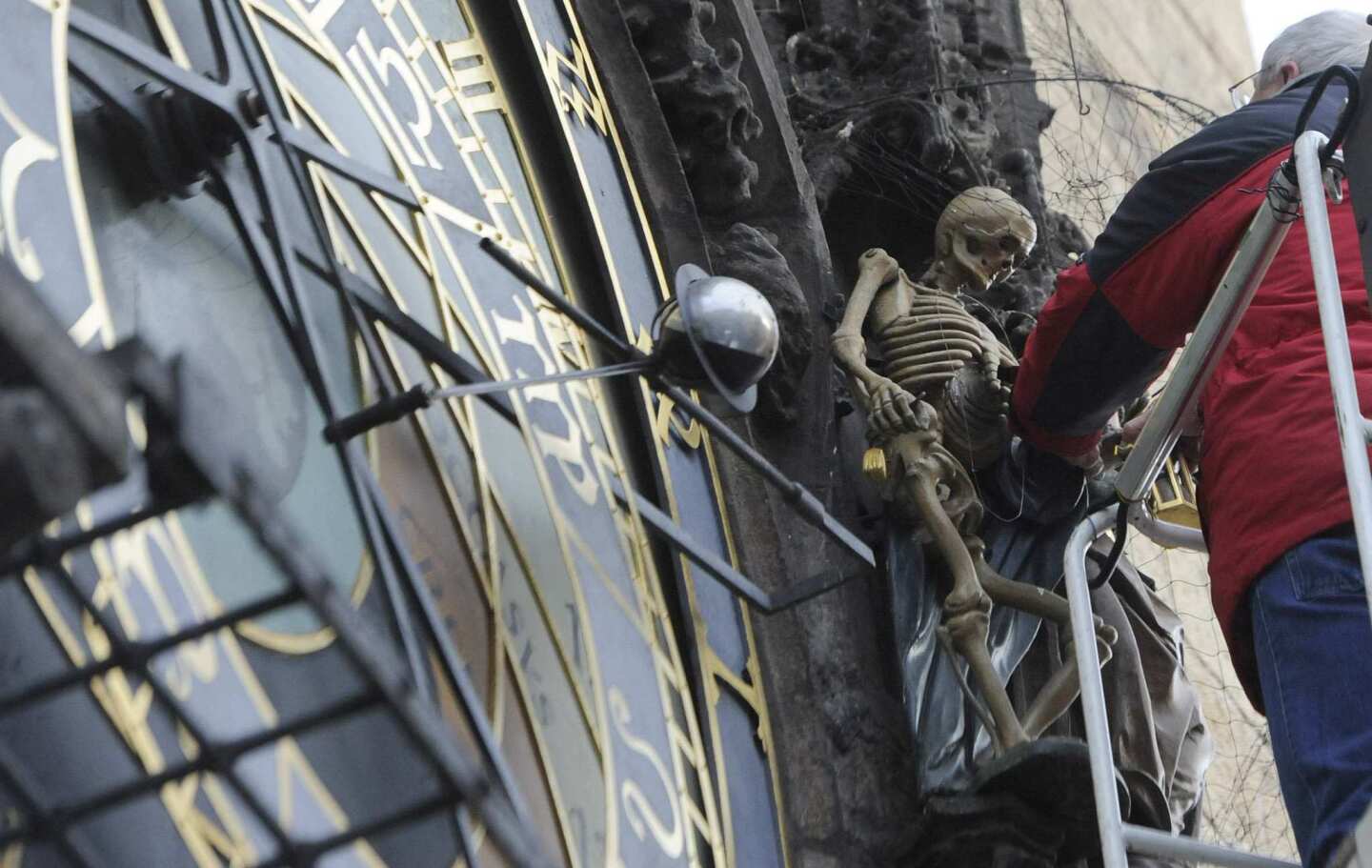 A worker removes the statue of Death for repairs. Death tolls the bell at each hour.