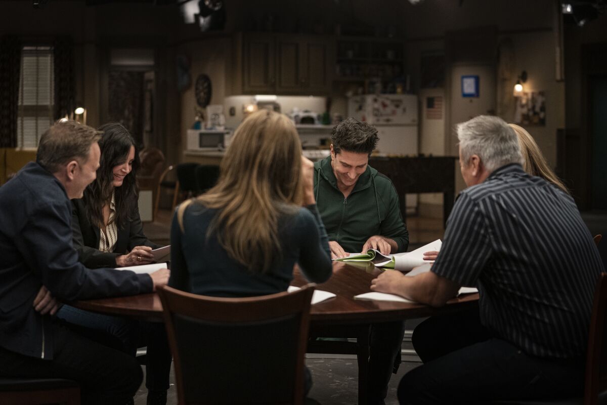 "Friends" cast members read scripts around a table.