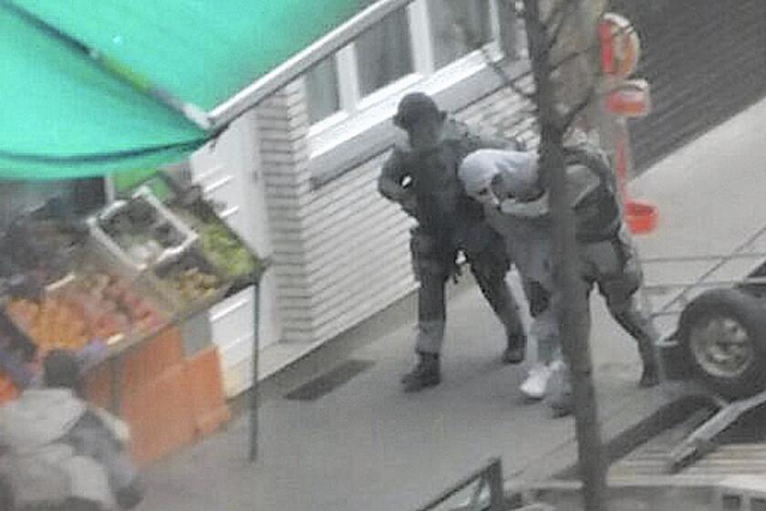 Police detain a man in Brussels' Molenbeek district on March 19 who is believed to be connected to a suspect in the Paris attacks. Residents say the district shouldn't be demonized for the actions of a few.