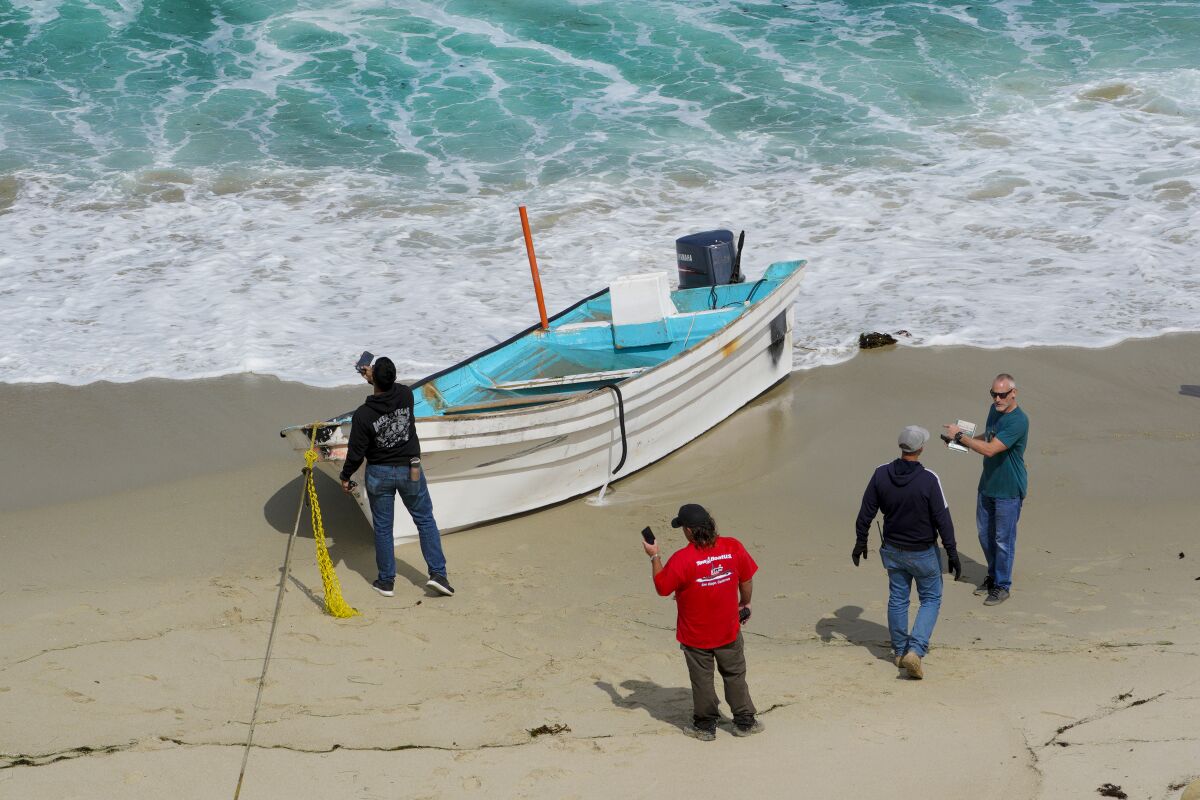 Investigators look over a small boat that beached in La Jolla after it got into rough water May 20.