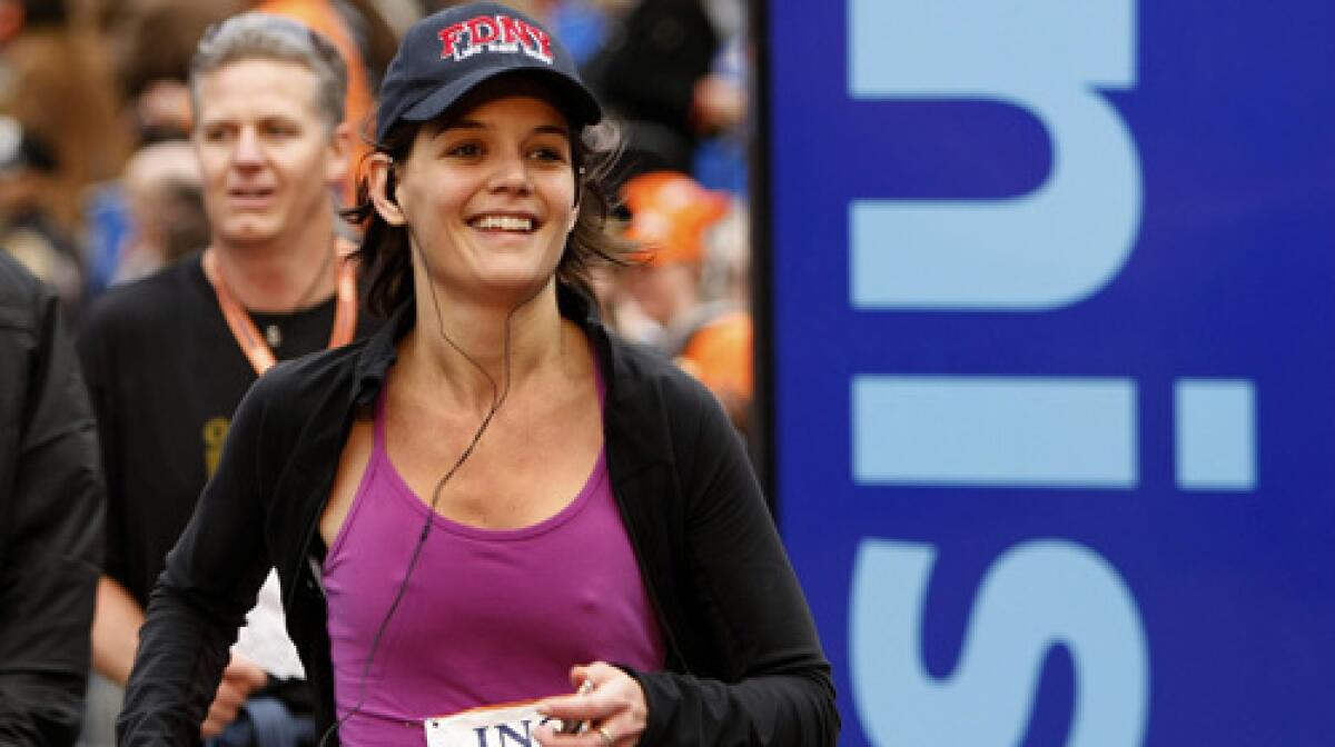 Katie Holmes crosses the finish line and runs to husband Tom Cruise and daughter Suri after completing the New York City Marathon.
