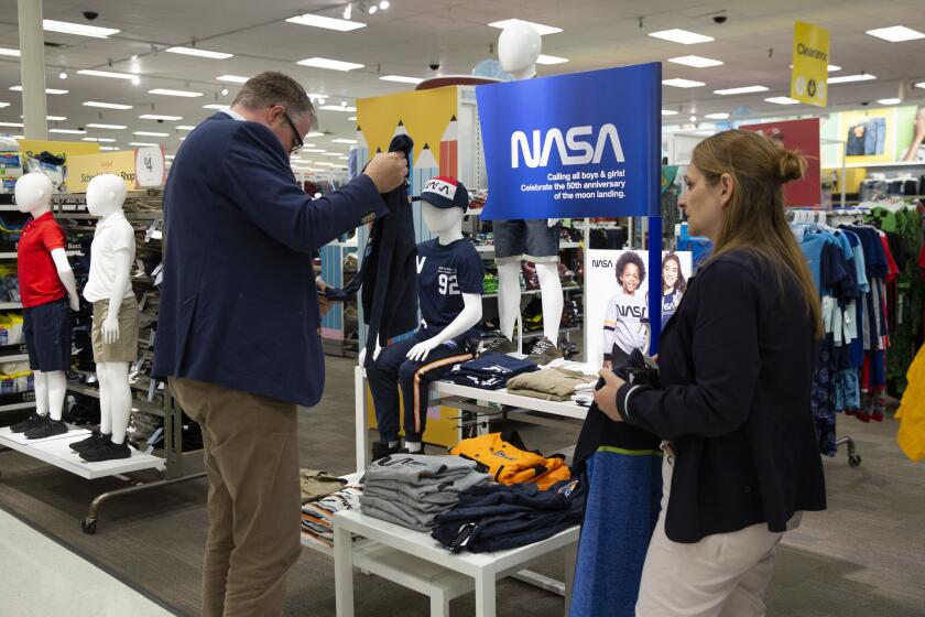 MANHATTAN BEACH, CALIF. - JULY 18, 2019: Colleagues Markus Gerold, left, and Ingrid Hausmann, who are visiting the US on business from Germany, look at NASA apparel to get as gifts for their sons at the Manhattan Beach Target in Manhattan Beach, Calif. on Thursday, July 18, 2019. (Liz Moughon / Los Angeles Times)