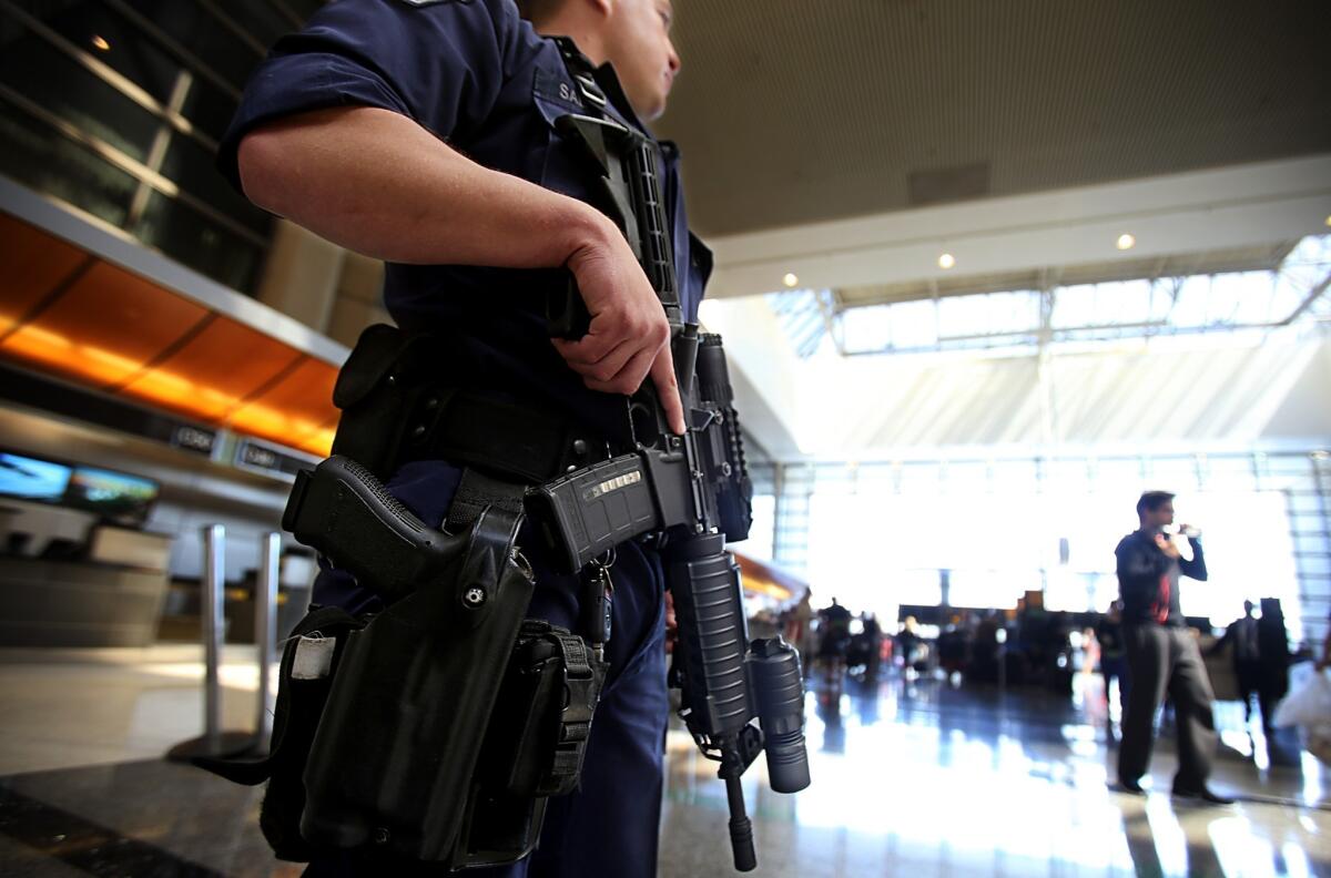 A heavily armed Los Angeles Airport Police Department officer stands guard at the Tom Bradley International Terminal at LAX. Months before a gunman's rampage le ft a TSA agent there dead, the department had changed its policy on the stationing of armed officers.
