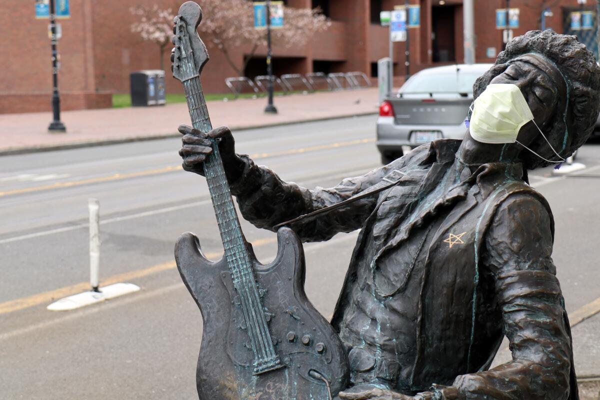 A face mask adorns the "The Electric Lady Studio Guitar," Daryl Smith's statue of late rock guitarist Jimi Hendrix, in Seattle.