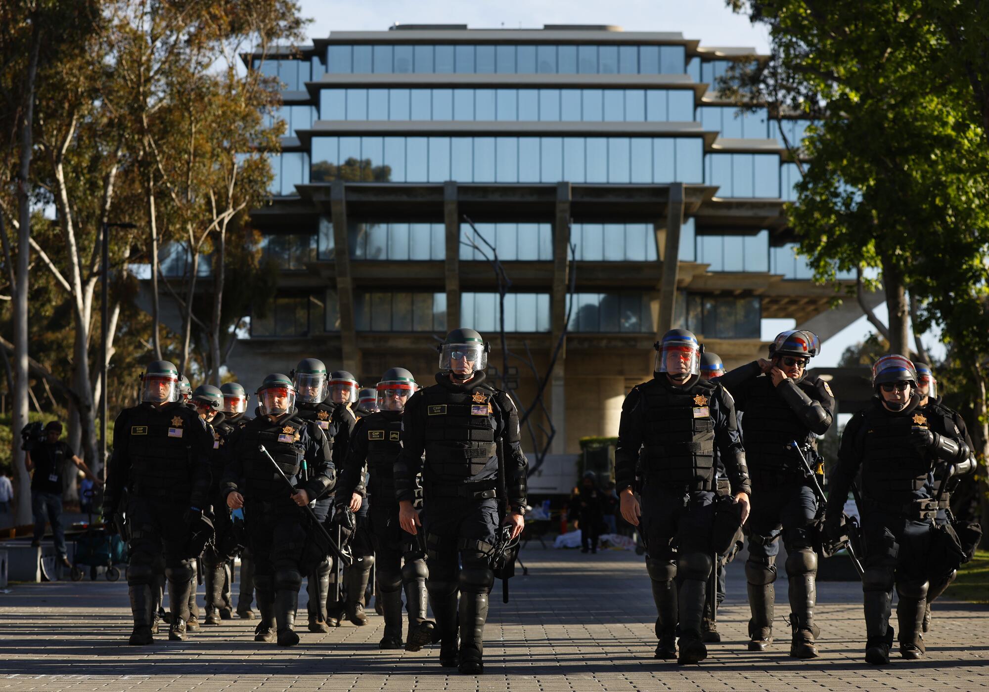 CHP officers walk down Library Walk at UC San Diego after arresting Pro-Palestinian protesters and breaki