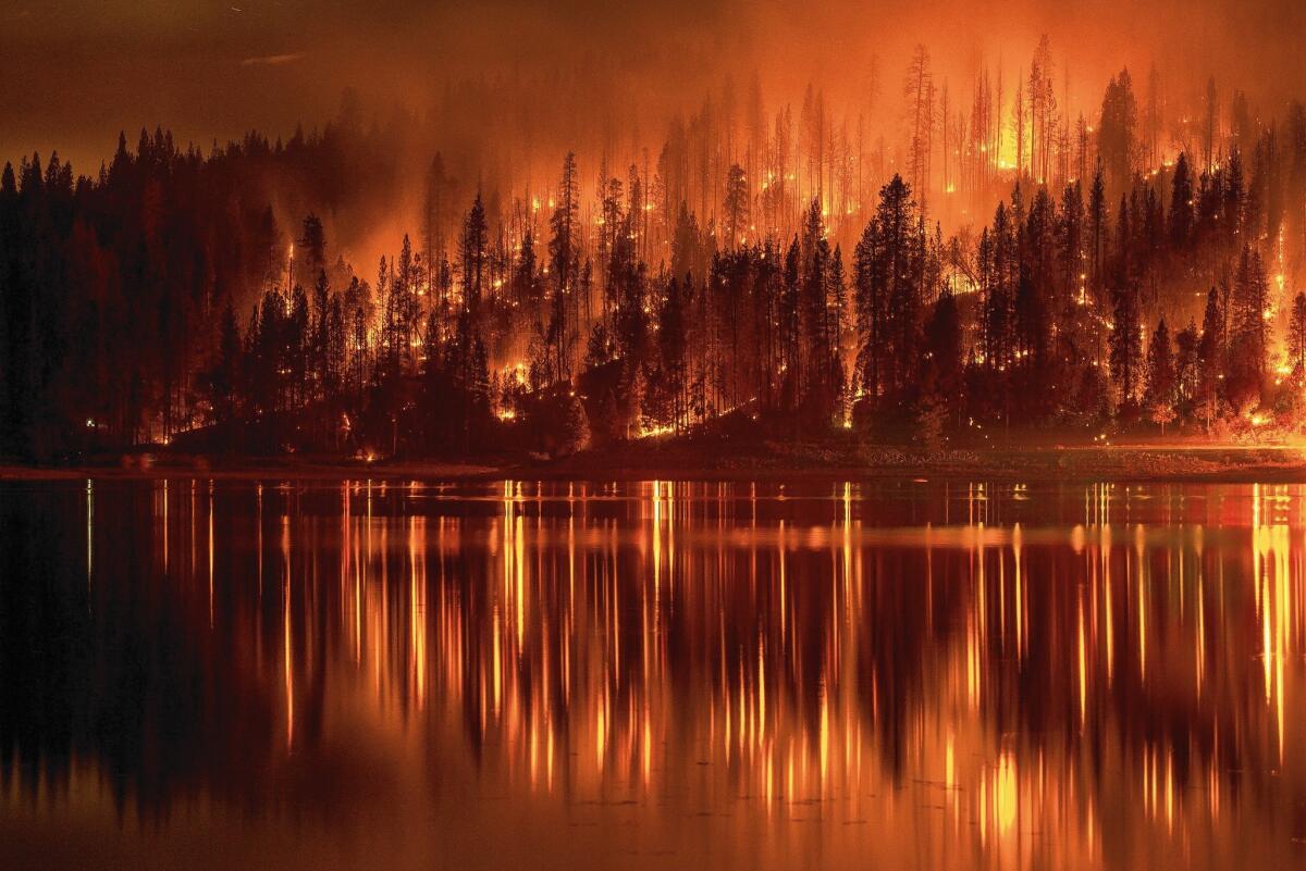 A wildfire approaches the shore of Bass Lake, one of eight uncontained large fires in California.
