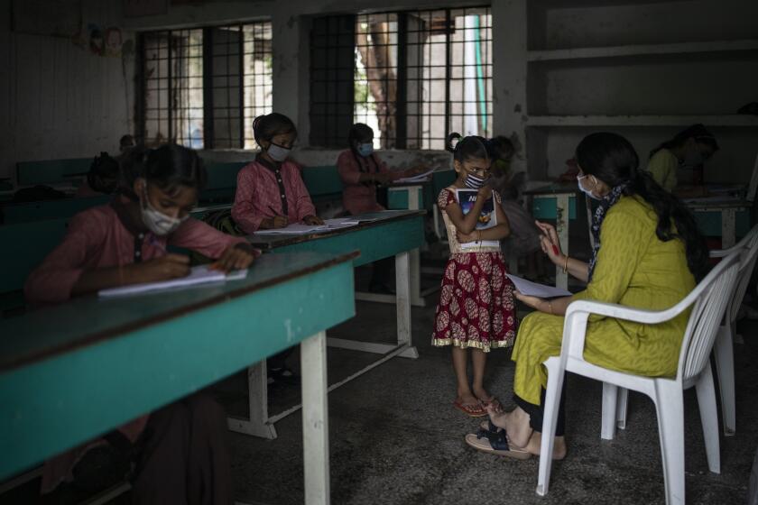 Students attend a class on the first day of partial reopening of schools in Noida, a suburb of New Delhi, India, Wednesday, Sept. 1, 2021. Many students in India will be able to step inside a classroom for the first time in nearly 18 months from Wednesday, as authorities have given the green light to partially reopen schools despite apprehension from some parents and signs that coronavirus infections are picking up again. Schools and colleges in least six states will reopen in a gradual manner with health measures in place throughout September. In New Delhi, all staff must be vaccinated and class sizes will be capped at 50% with staggered seating and sanitized desks. (AP Photo/Altaf Qadri)